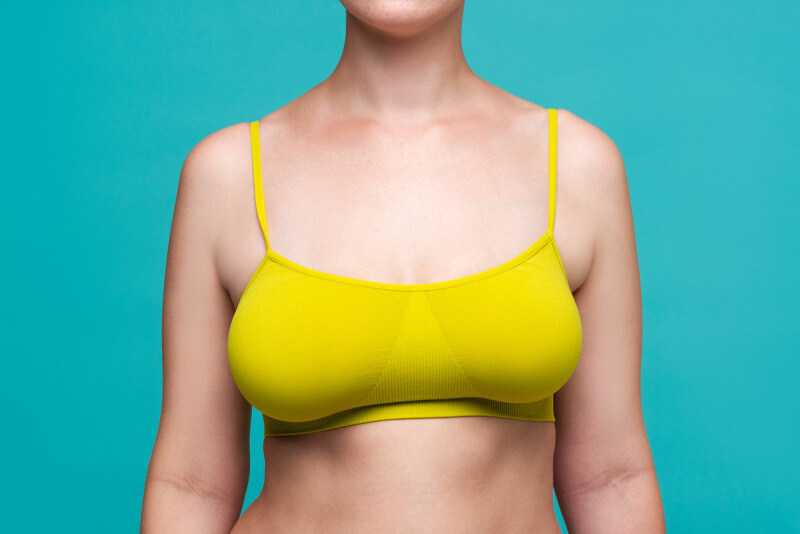 https://www.njcenterforcoolsculpting.com/wp-content/uploads/2021/08/Woman-in-yellow-top-bra-with-big-natural-breasts-on-blue-background.jpg